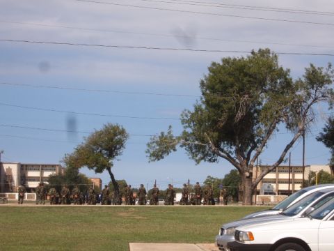1988 Ford Bronco - Soldiers stand in formation on a sunny day, with buildings and trees visible behind them.
