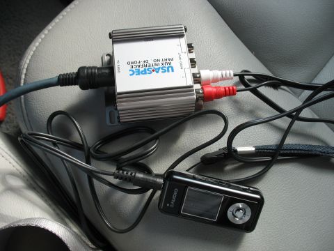 2003 Ford Crown Victoria - An aftermarket car audio interface and an mp3 player are connected and resting on a gray car seat.