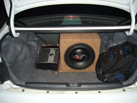 1997 Ford Probe - The trunk of a white car contains a subwoofer, amplifier, and a black bag.