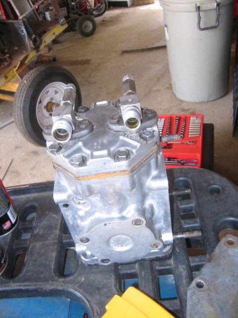 1995 Ford Bronco - A silver hydraulic pump is displayed on a black tray, with a red toolbox and a tire visible in the background.