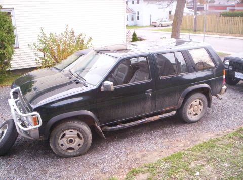 1990 Jeep Cherokee - This SUV is parked outside next to another vehicle, with a spare tire resting on the ground.