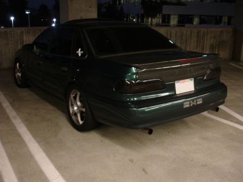 1993 Ford Taurus - Rear view of a 1993 Ford Taurus parked in a garage, showing custom taillights and trunk.