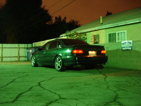 1993 Ford Taurus - A green sedan is parked in a lot at night, illuminated by artificial lighting.