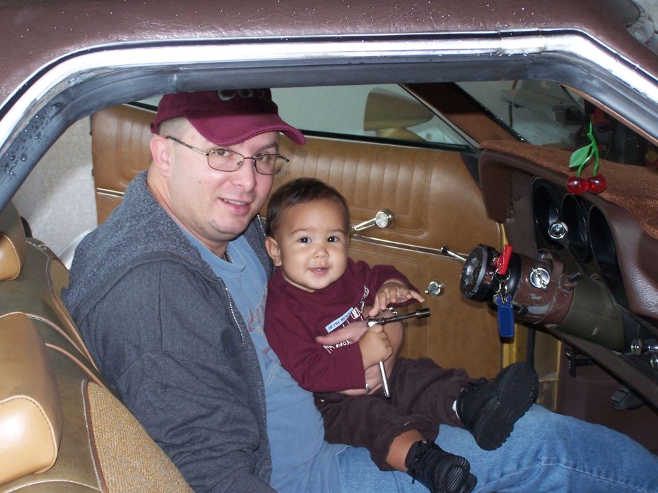 1973 Ford Ranchero interior with man and baby, brown upholstery, dashboard visible