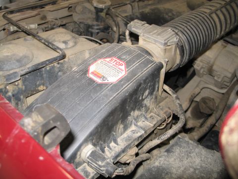 1995 Ford Bronco - Close-up of a dusty engine air intake system, a prominent warning sticker.