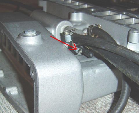 1986 Ford Bronco - Close-up of an engine intake manifold, with a red arrow highlighting a vacuum line connection.