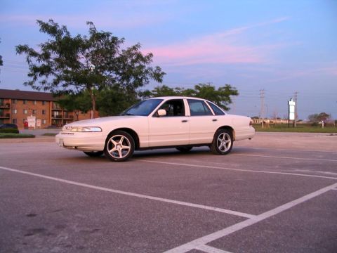 2003 Ford Crown Victoria - A white sedan is parked in a lot during dusk. The sky has pink and blue hues.
