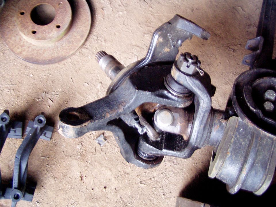 Front axle assembly with brake rotor and suspension components on a dirt surface