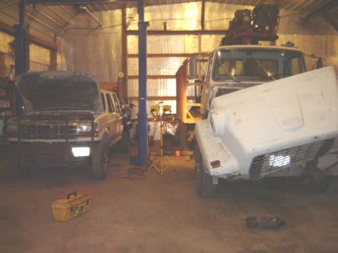 1992 Ford Bronco - A 1992 Ford Bronco is in a garage with its hood open, parked next to a white truck.