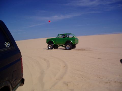 1986 Ford Bronco - Two vehicles on sand dunes under a clear blue sky.