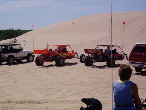 1986 Ford Bronco - Several off-road vehicles are parked on sand dunes on a sunny day.