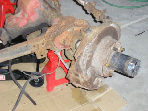 1996 Ford Bronco - This is a rusted rear axle assembly with brake components, placed on jack stands for work.