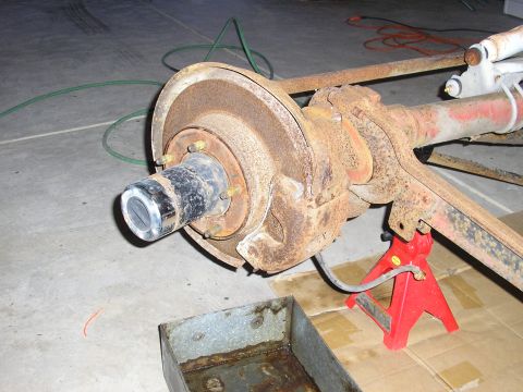 1996 Ford Bronco - A heavily rusted rear axle assembly is supported by red jack stands in a garage setting.