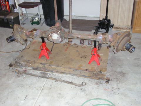 1996 Ford Bronco - A disassembled rear axle assembly is supported by red jack stands in a garage setting.