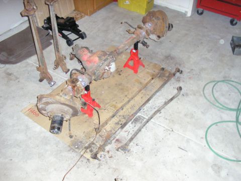 1996 Ford Bronco - Disassembled vehicle axles and suspension components are shown on a garage floor.