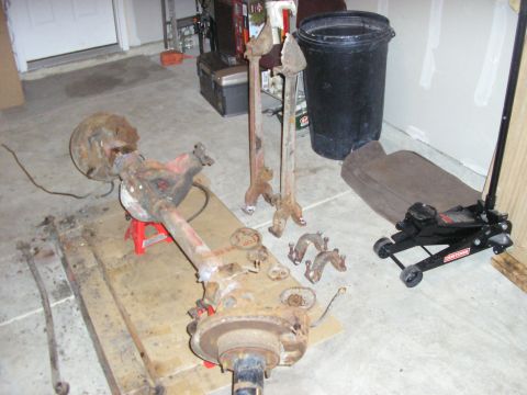 1996 Ford Bronco - Disassembled vehicle rear axle assembly and associated parts are laid out on a garage floor.