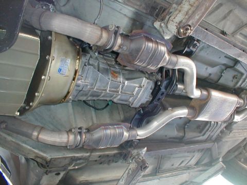 1993 Ford Thunderbird - The underside of a vehicle shows its transmission and exhaust components, including catalytic converters.