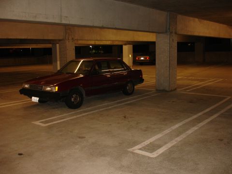 1993 Ford Taurus - A maroon sedan is parked in a dimly lit garage, with another vehicle visible in the background.