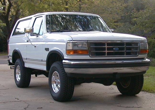 White Ford Bronco SUV, front three-quarter view, chrome grille and bumper, parked outdoors.