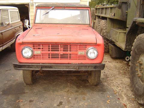 2006 Ford F1 - A red SUV with a distinctive grille and round headlights is parked next to other vehicles.