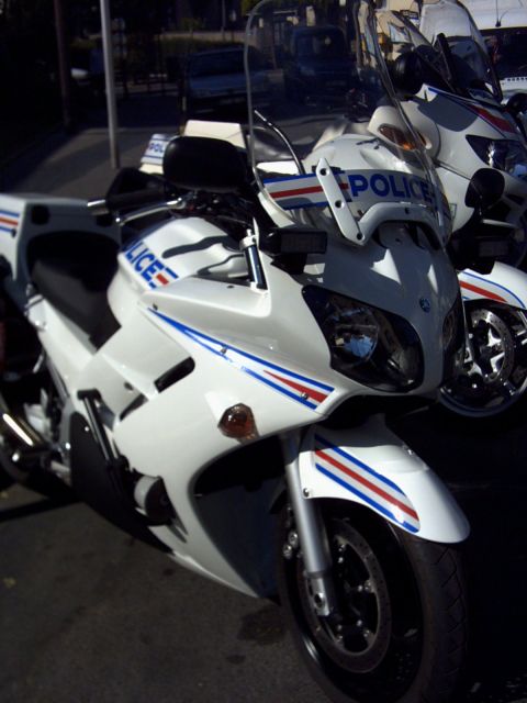 1991 Ford Crown Victoria - Two white police motorcycles are parked side-by-side, one in the foreground and another behind it.