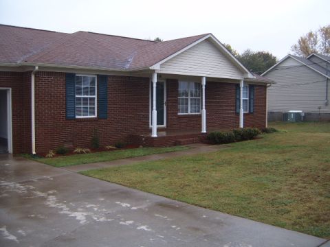 1988 Ford Bronco - A suburban home with a red brick exterior and a covered front porch is shown on an overcast day.