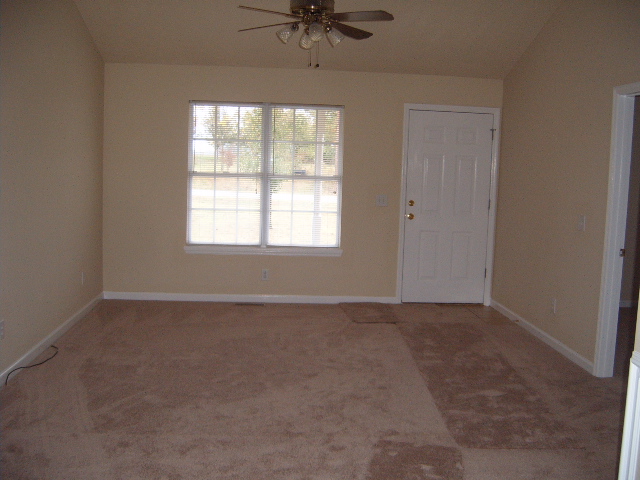 Interior room with beige walls, carpet, a window, and a white door