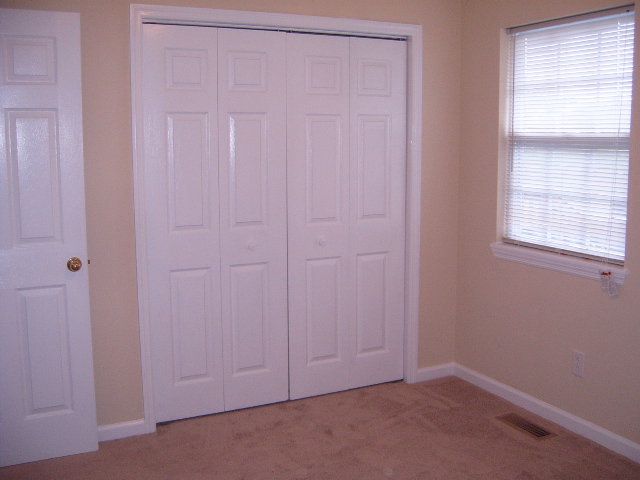Interior room scene with bi-fold closet doors and a window