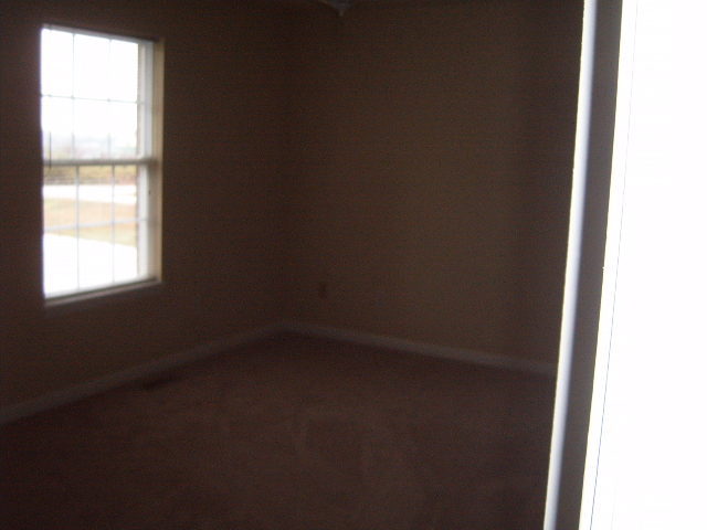 Interior room with brown walls, carpet, and a window showing an overcast sky