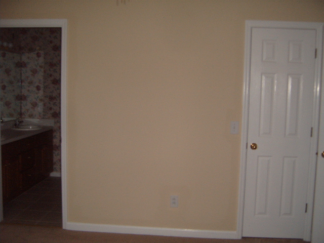 Interior view of a room with a doorway to a bathroom and a closed white door