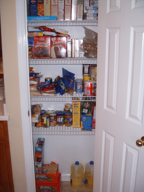 1988 Ford Bronco - A pantry is filled with various food items on wire shelves, with a white door open to the right.