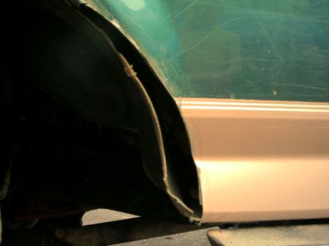 1996 Ford Bronco - Detail of a vehicle's fender well and lower body panel, with visible damage and a Supermotors watermark.