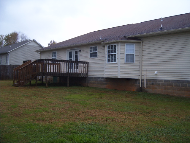 Backyard scene with a wooden deck and a beige house