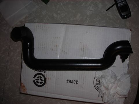 1995 Ford Bronco - A black metal automotive pipe is shown resting on a cardboard box, with a cell phone visible in the background.