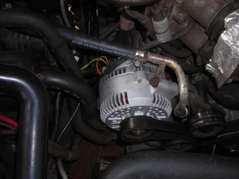 1995 Ford Bronco - Close-up of an alternator and heater hose assembly within an engine compartment.