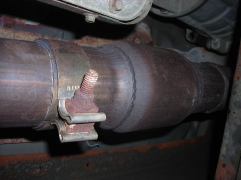 1995 Ford Bronco - Close-up view of a vehicle's exhaust system, showing a clamp and catalytic converter with visible rust.