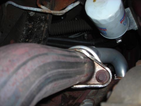 1995 Ford Bronco - Close-up view of an exhaust pipe connection and oil filter, likely from a vehicle's engine bay.