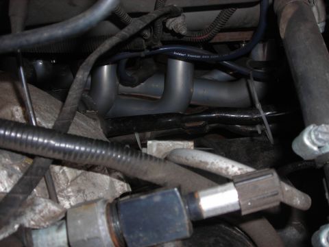 1995 Ford Bronco - Close-up view of engine components, including an exhaust manifold, with "SUPERMOTORS" branding visible.