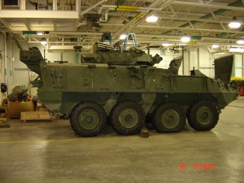1990 Ford Bronco - Side view of a military armored vehicle with six wheels inside a building.