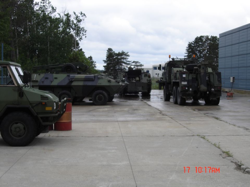 Several military vehicles parked on a concrete lot