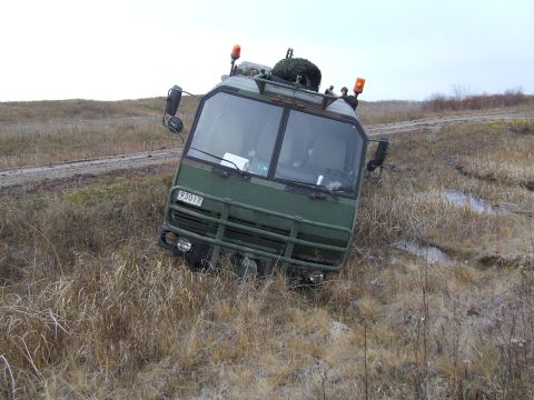 1990 Ford Bronco - This military truck appears to be stuck in a muddy ditch off a dirt road.