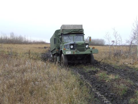 1990 Ford Bronco - Military truck with license plate 58852 navigating through a muddy field.