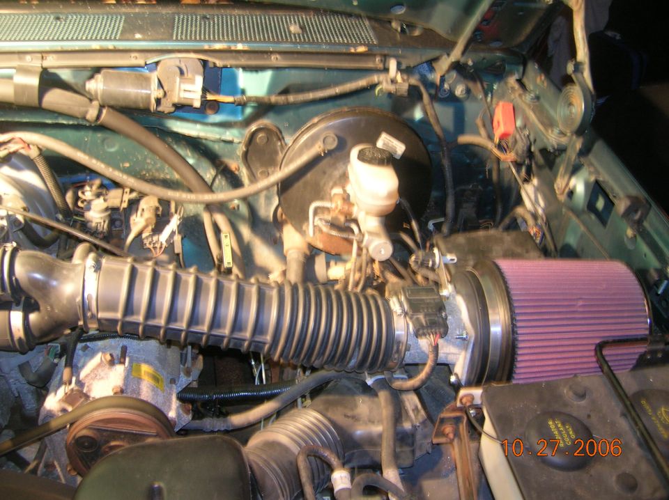 Engine bay with a K&N air filter and intake hose. Teal green paint visible