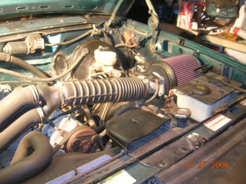 1996 Ford Bronco - Engine bay of a teal-green truck shot from the driver's side with the hood open, showing a red K&N-style cone air filter on a metal intake…