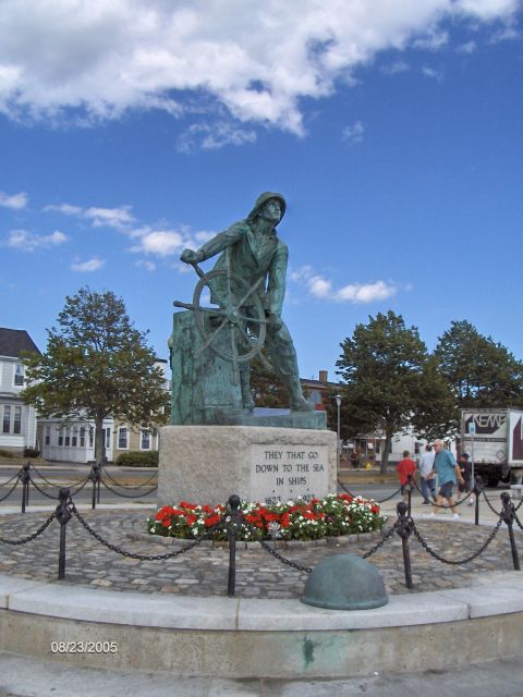 1996 Mercury Grand Marquis - A statue of a fisherman at a ship's wheel stands in a plaza, with an inscription on its base and a date stamp of 08/23/2005.