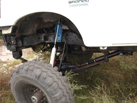 1989 Ford Bronco - Close-up view of the suspension and wheel well of a white Ford Bronco.