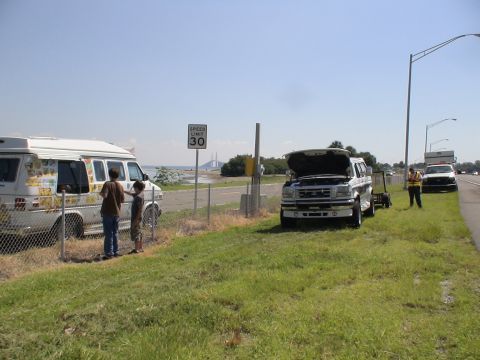 1993 Ford C-350 (Centurion Conversions) - A white Ford F-Series truck with its hood open sits on the side of the road, near an ice cream truck and a speed limit sign.