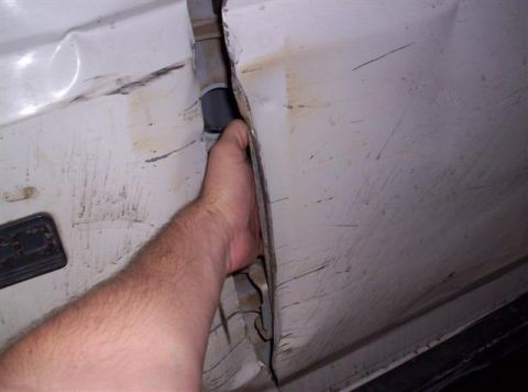 1995 Ford Bronco - A hand is shown reaching into the large gap between the doors of a damaged white vehicle.