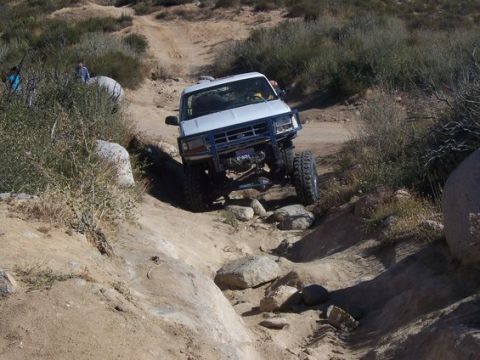 1995 Ford Bronco - This modified SUV navigates a challenging off-road obstacle course with steep inclines and large rocks.