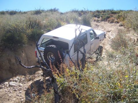 1995 Ford Bronco - This 1995 Ford Bronco is shown on a challenging off-road path, surrounded by dry vegetation and dirt.
